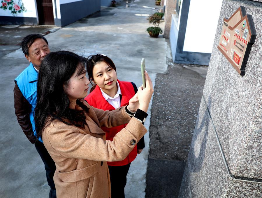 浙江省长兴县李家巷镇刘家渡村村民（前）在党员志愿者的指导下，用手机扫描二维码（“村务e点通”），查看最新的文明诚信档案考评结果（2019年11月28日摄）。 新华社记者 徐昱 摄