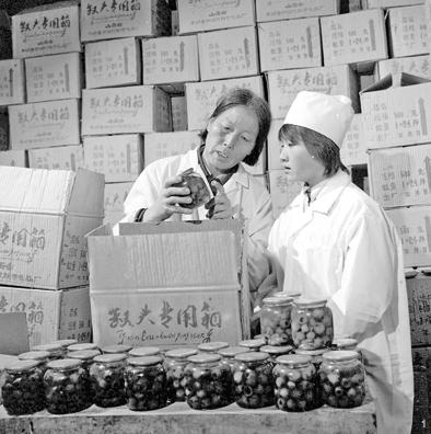△1986年9月 申纪兰(左)和工人一起检查罐头质量